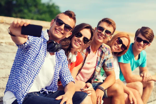 Grupo de amigos sonrientes con teléfono inteligente al aire libre — Foto de Stock