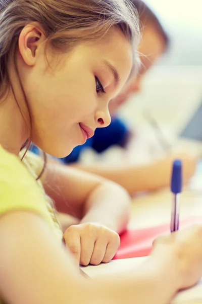 Close up of school kids writing test in classroom — Stock Photo, Image