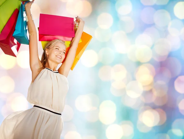 Mujer feliz joven con bolsas de compras sobre luces —  Fotos de Stock