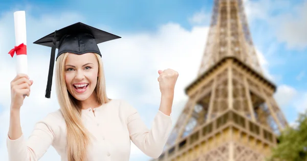 Student in trencher with diploma over eiffel tower — Stock fotografie