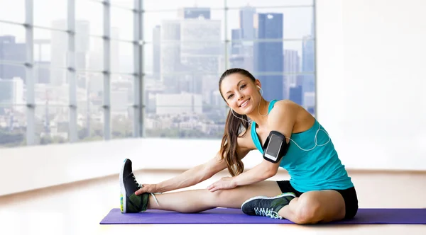 Smiling woman stretching leg on mat over gym — Stock Photo, Image