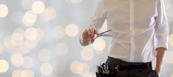 Primer plano de estilista masculino con tijeras sobre luces —  Fotos de Stock