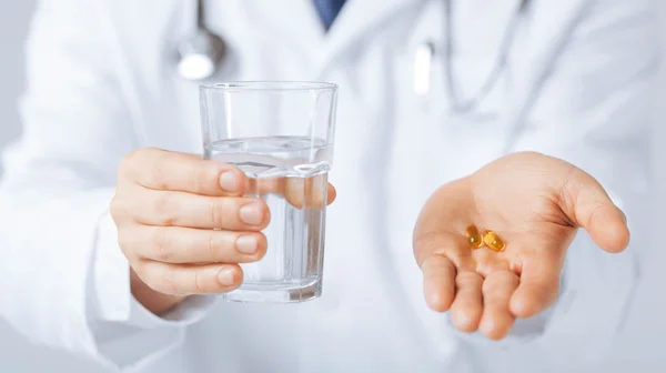 Ręce lekarza dające kapsułkę i szklankę wody — Zdjęcie stockowe