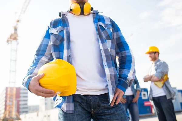 Gros plan du constructeur tenant le casque de sécurité au bâtiment — Photo