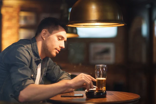 Man drinking beer and smoking cigarette at bar — Stock Photo, Image