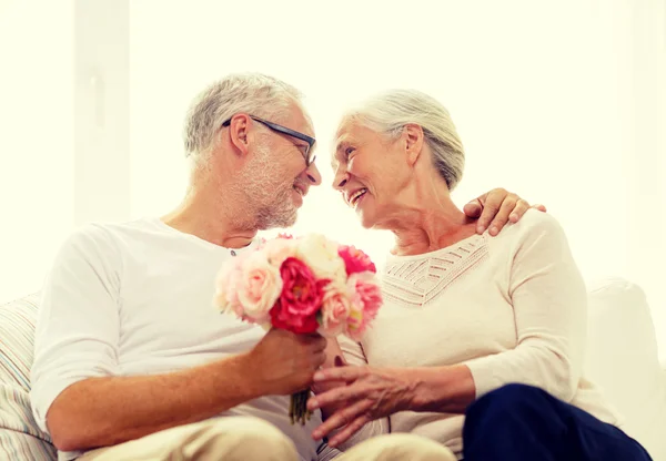 Happy senior couple with bunch of flowers at home — Stock Photo, Image