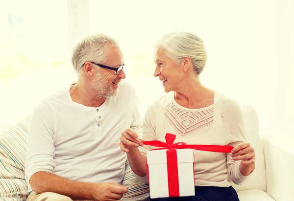 Heureux couple aîné avec boîte cadeau à la maison — Photo