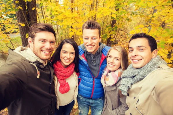 Groep van mannen en vrouwen in de herfst park glimlachen — Stockfoto