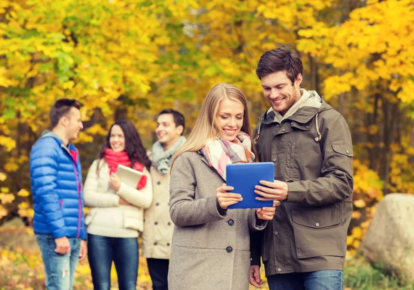 Gruppe lächelnder Freunde mit Tabletten im Park — Stockfoto