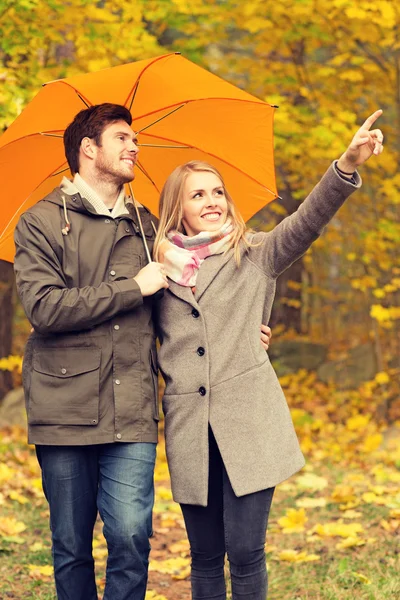Улыбающаяся пара с зонтиком в осеннем парке — стоковое фото