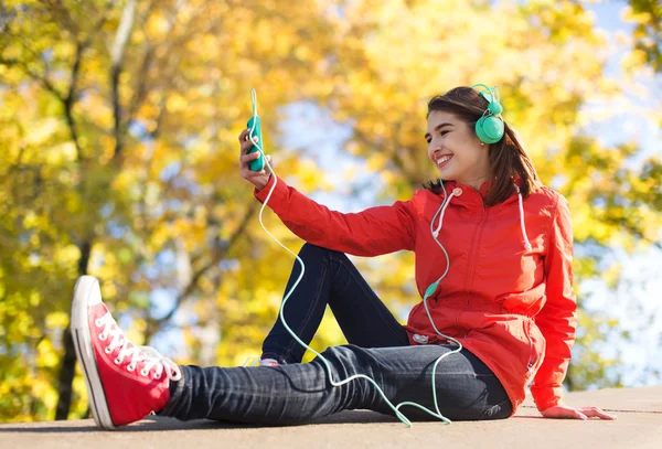 Gelukkig jonge vrouw met smartphone en hoofdtelefoons — Stockfoto