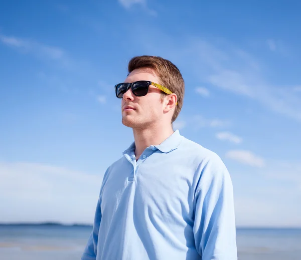 Jeune homme en lunettes de soleil à la plage d'été — Photo