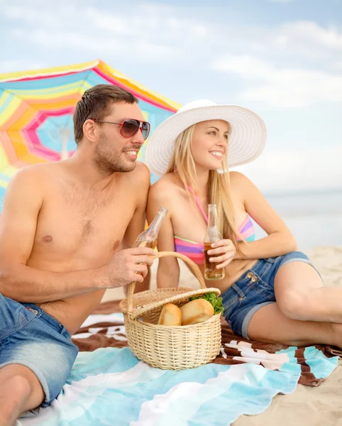 Casal feliz fazendo piquenique e banhos de sol na praia — Fotografia de Stock