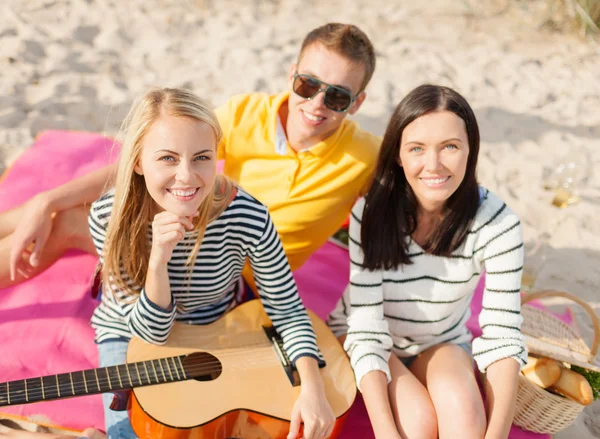 Groupe d'amis heureux jouant de la guitare sur la plage — Photo