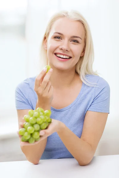 Happy woman eating grapes at home — Stock Photo, Image