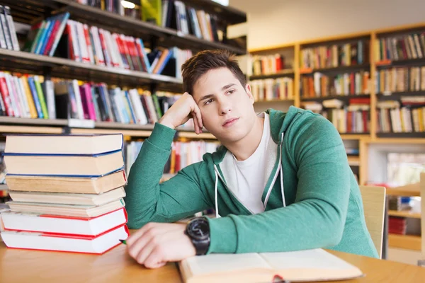 Znudzony student lub młody człowiek z książek w bibliotece — Zdjęcie stockowe