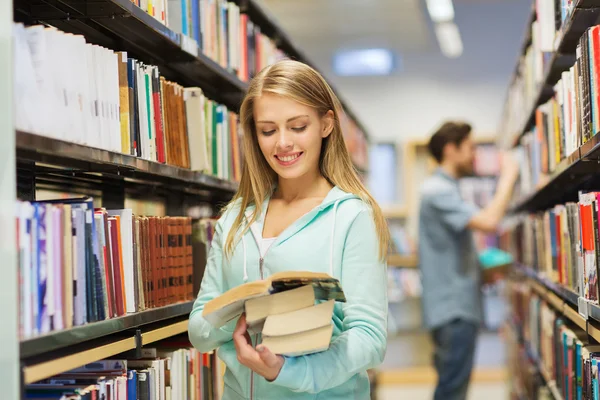 Lycklig student tjej eller kvinna med bok i biblioteket — Stockfoto