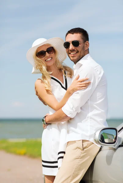 Feliz hombre y mujer abrazándose cerca de coche en el mar — Foto de Stock