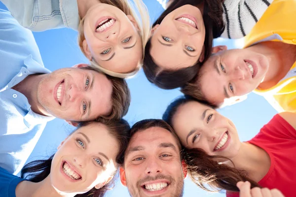 Smiling friends in circle on summer beach Stock Photo