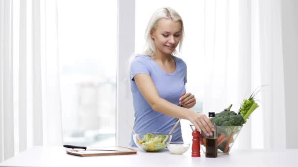 Lachende vrouw koken plantaardige salade thuis — Stockvideo