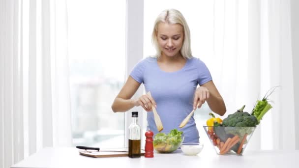 Улыбающаяся женщина готовит овощной салат дома — стоковое видео