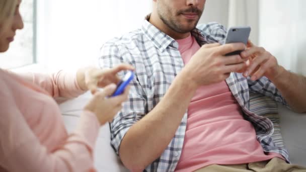 Pareja con teléfonos inteligentes mensajes de texto en casa — Vídeos de Stock