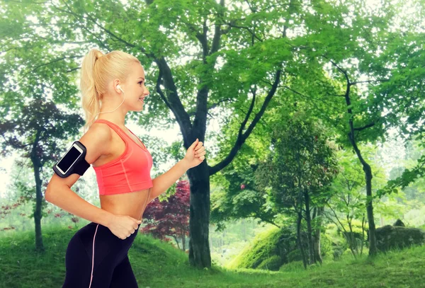 Mujer deportiva corriendo con smartphone y auriculares — Foto de Stock