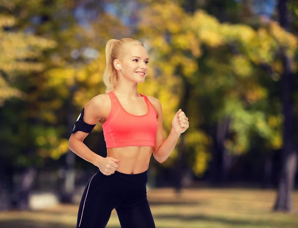 Mujer deportiva corriendo con smartphone y auriculares —  Fotos de Stock