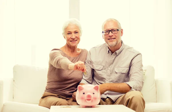 Senior couple with money and piggy bank at home — Stock Photo, Image