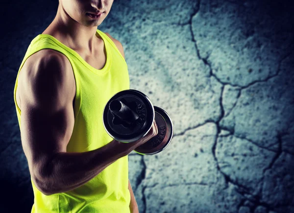 Close up of young man with dumbbell flexing biceps — Stock Photo, Image