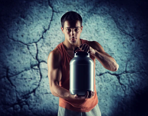 Jovem fisiculturista masculino segurando frasco com proteína — Fotografia de Stock