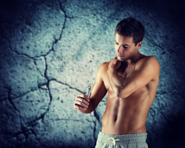 Joven culturista masculino aplicando gel de alivio del dolor — Foto de Stock