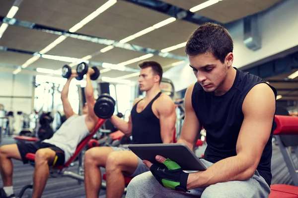群与 tablet pc 和哑铃在健身房的男人 — 图库照片