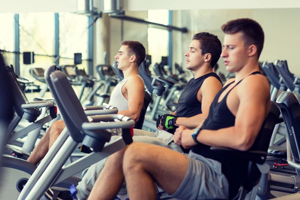 Uomini che si allenano in cyclette in palestra — Foto Stock