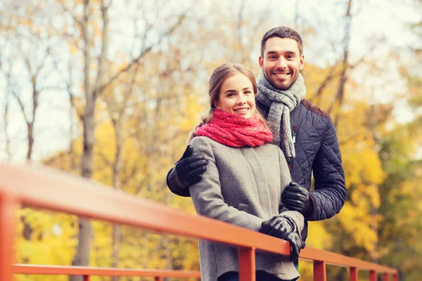 Χαμογελαστά, ζευγάρι αγκαλιάζει στη γέφυρα στο πάρκο φθινόπωρο — Φωτογραφία Αρχείου