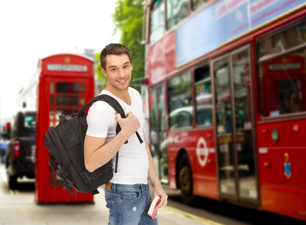 Happy young man with backpack and book travelling — Stock Photo, Image