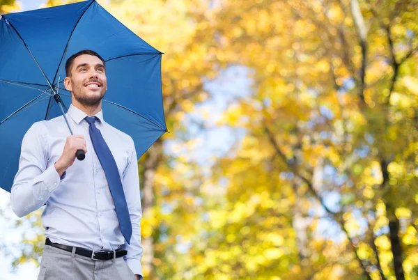Businessman with umbrella over autumn background — Stock Photo, Image