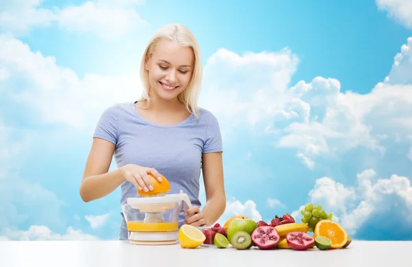 Smiling woman squeezing fruit juice over sky — Stockfoto