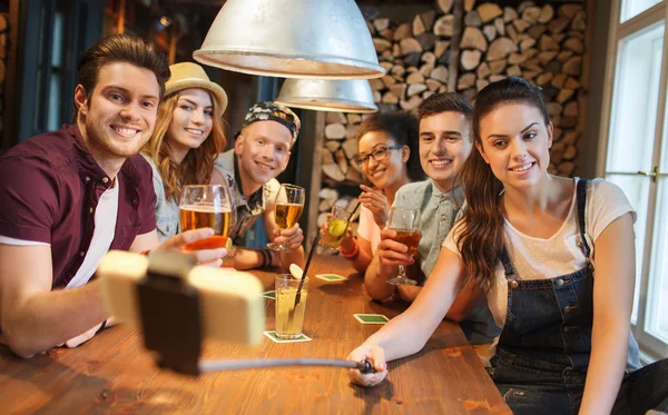 Vänner med smartphone på selfie sticka på bar — Stockfoto