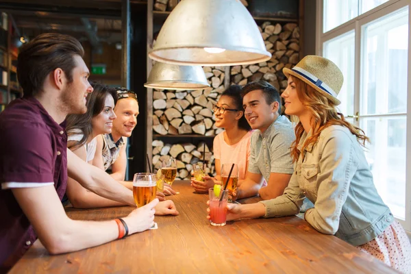 Amigos felizes com bebidas conversando no bar ou pub — Fotografia de Stock