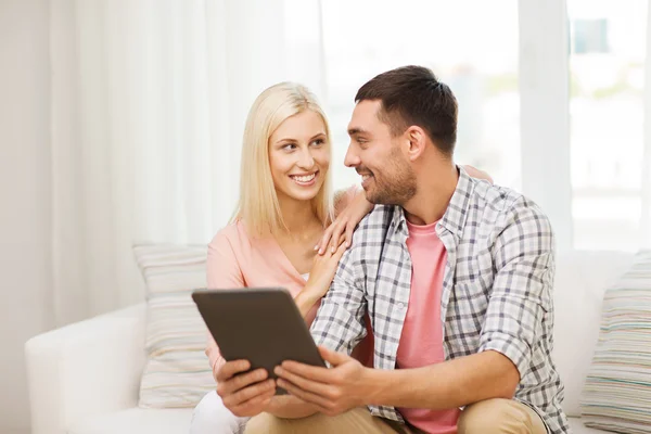 Lachende gelukkige paar met de tablet pc thuis — Stockfoto