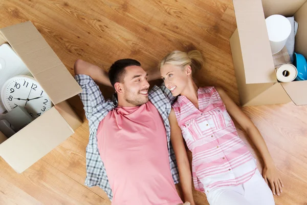 Happy couple lying on floor among cardboard boxes — ストック写真