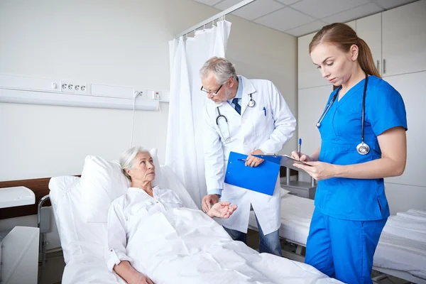 Médico y enfermera visitando a una mujer mayor en el hospital — Foto de Stock