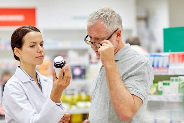 Pharmacist showing drug to senior man at pharmacy — Stock Photo, Image