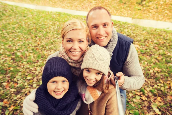 Familia feliz con palo selfie en el parque de otoño —  Fotos de Stock