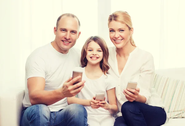 Föräldrar och liten flicka med smartphones hemma — Stockfoto