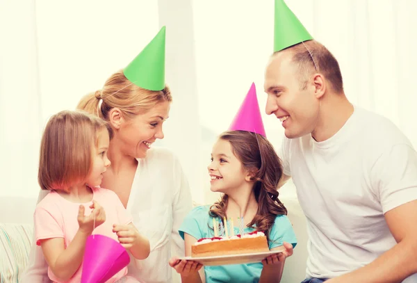 Smiling family with two kids in hats with cake — Stock Photo, Image