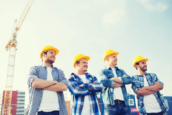 Groep van lachende bouwers in hardhats in openlucht — Stockfoto