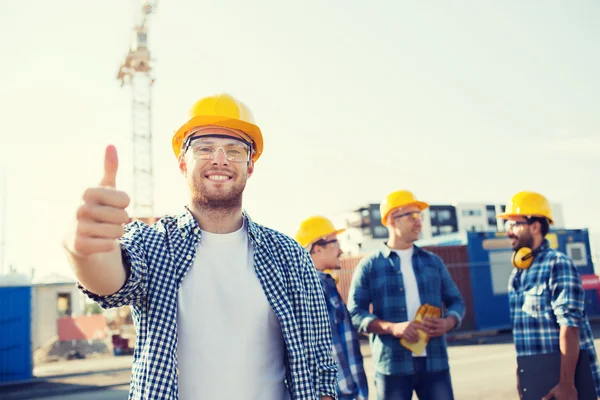 Grupo de construtores sorridentes em hardhats ao ar livre — Fotografia de Stock