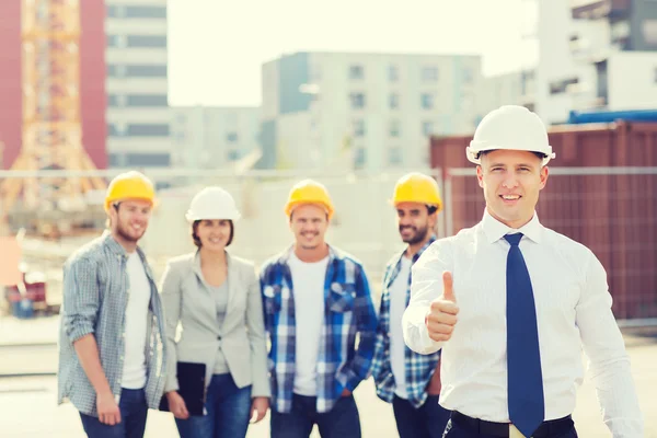 Gruppo di costruttori sorridenti in hardhats all'aperto — Foto Stock